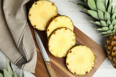 Photo of Slices of fresh pineapple on white wooden table, flat lay