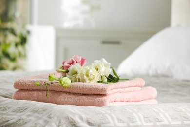 Terry towels with beautiful flowers on bed indoors, space for text