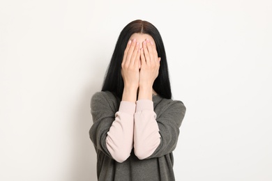 Upset young woman crying against white background