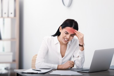 Woman suffering from migraine at workplace in office 