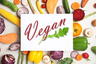 Paper card with word Vegan and fresh vegetables on white background, flat lay