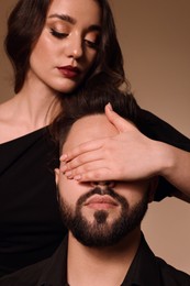 Bearded man with sexy lady on light brown background