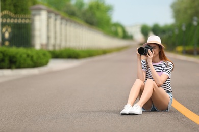 Photographer taking photo with professional camera on road. Space for text