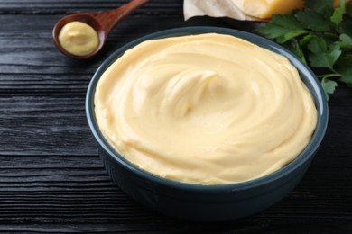 Tasty cheese sauce in bowl on black wooden table, closeup