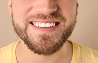 Young man with healthy teeth on color background, closeup