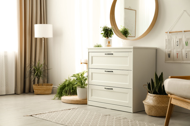 Stylish room interior with chest of drawers and round mirror