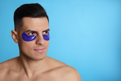 Man with under eye patches on light blue background. Space for text