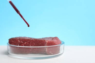 Dripping red liquid onto sample of lab grown meat on white table. Space for text