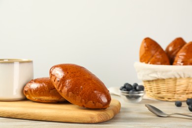 Delicious baked pirozhki on wooden table, space for text