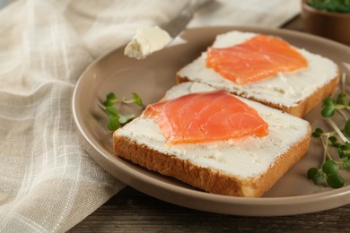 Photo of Delicious sandwiches with cream cheese and salmon on wooden table, closeup