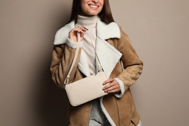 Fashionable young woman with stylish bag on beige background, closeup