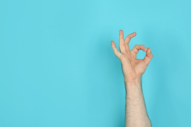 Young man showing OK gesture on color background. Space for text