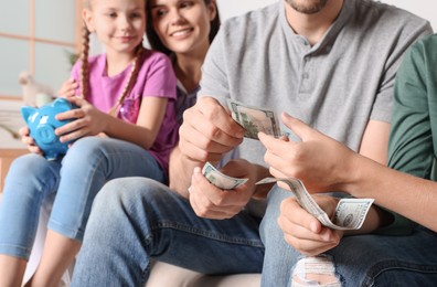 Happy family with money and piggy bank at home, closeup