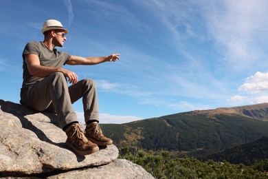 Man enjoying picturesque view on cliff in mountains. Space for text