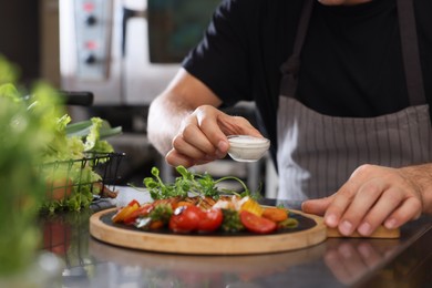 Photo of Professional chef putting bowl of sauce to delicious cooked dish in restaurant kitchen, closeup