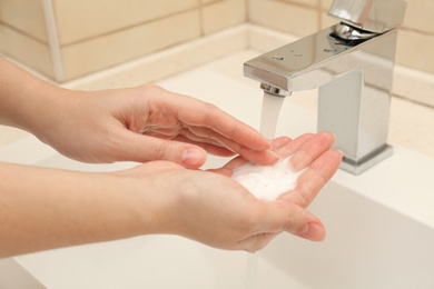 Photo of Woman washing hands with antiseptic soap in bathroom, closeup