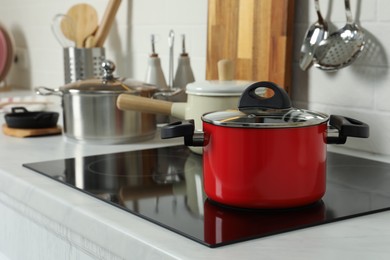 Red pot on electric stove in kitchen. Cooking utensil
