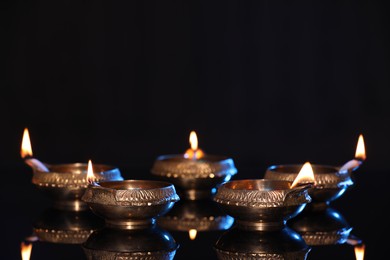 Many lit diyas on black background, space for text. Diwali lamps