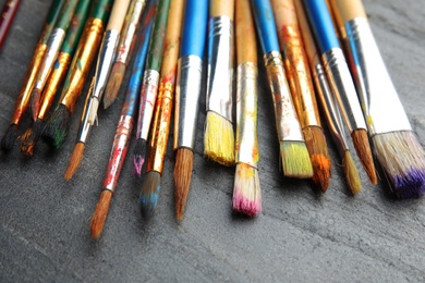 Different paint brushes on grey table, closeup