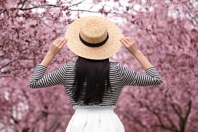 Young woman in park with blooming trees. Spring look
