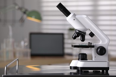 Photo of Modern medical microscope on metal table in laboratory, space for text