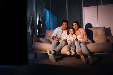 Photo of Family watching movie with popcorn on sofa at night