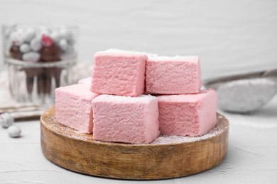 Photo of Tasty marshmallows with powder sugar on white textured table, closeup