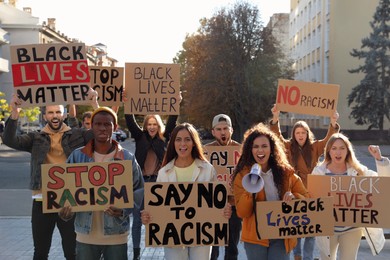 Protesters demonstrating different anti racism slogans outdoors. People holding signs with phrases