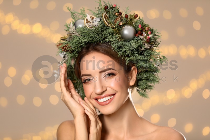Photo of Beautiful young woman wearing Christmas wreath against blurred festive lights