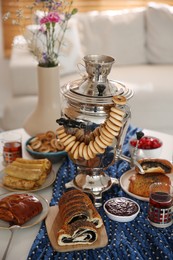 Traditional Russian samovar with treats on white table at home