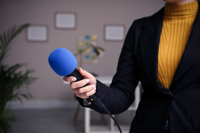Professional journalist with modern microphone in room, closeup