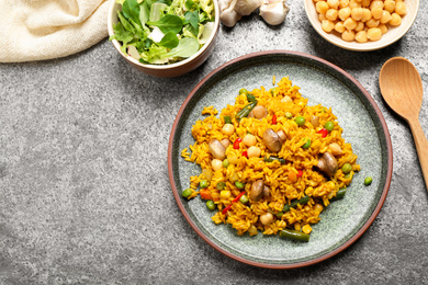 Delicious rice pilaf with vegetables on grey table, flat lay. Space for text