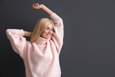 Happy woman in stylish sweater on black background. Space for text