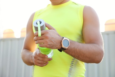 Man with fitness tracker and bottle of water after training outdoors, closeup