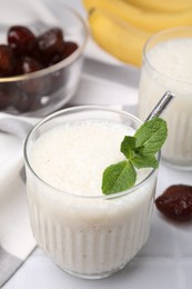 Photo of Glass of delicious date smoothie with mint on white table