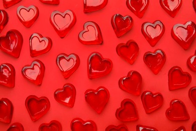 Many heart shaped jelly candies on red background, flat lay