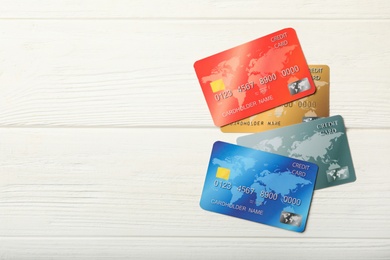 Different credit cards on white wooden table, flat lay. Space for text