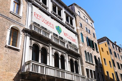 Banner with phrase WELCOME REFUGEES on building outdoors