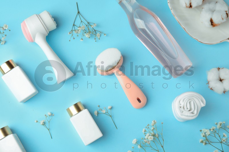 Photo of Flat lay composition with face cleansing brushes on light blue background. Cosmetic accessories