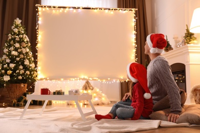 Father and daughter watching movie using video projector at home. Cozy Christmas atmosphere