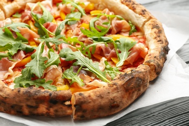 Photo of Tasty pizza with meat and arugula on grey wooden table, closeup