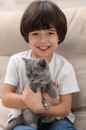 Cute little boy with kitten on sofa. Childhood pet