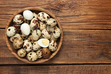 Photo of Unpeeled and peeled hard boiled quail eggs in bowl on wooden table, top view. Space for text