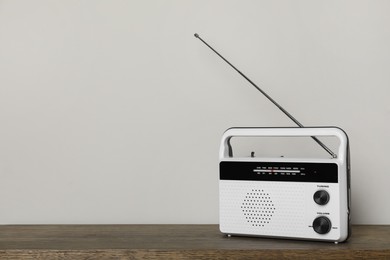 Retro radio receiver on wooden table against light grey background. Space for text