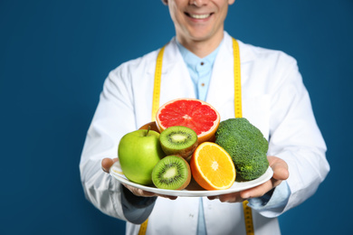 Nutritionist with healthy products on blue background, closeup
