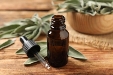 Bottle of essential sage oil, dropper and leaves on wooden table.