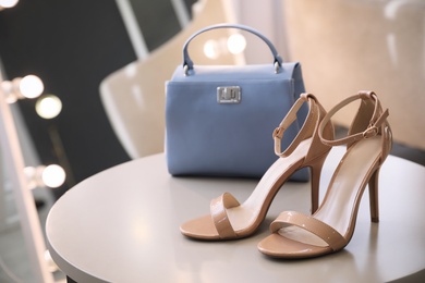 Stylish women's shoes and bag on table in modern boutique