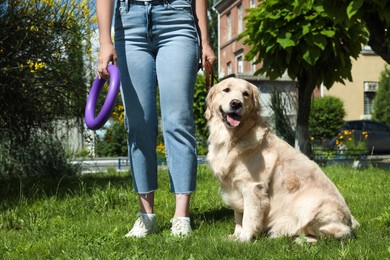 Woman walking Golden Retriever dog in sunny park, closeup