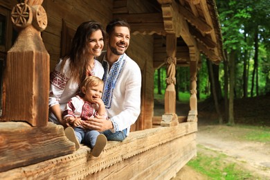 Happy family in Ukrainian national clothes on wooden terrace