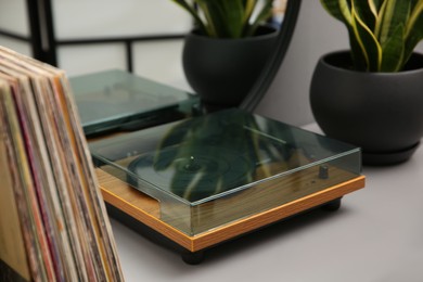 Stylish turntable and vinyl records on table indoors